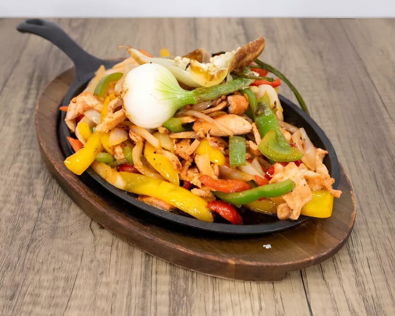 Sizzling chicken fajitas with colorful bell peppers and onions in a cast iron skillet.